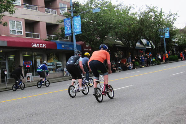 Adults on toddler bicycles on West 10th Avenue, Vancouver
